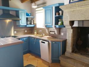 a kitchen with blue cabinets and a stove at Gîte Hydrangea in Lanhélin