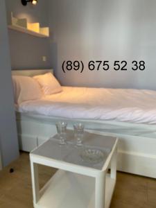 a room with a bed with a table with glasses on it at Apartament MRĄGOWIA in Mrągowo
