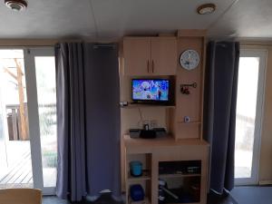a living room with a tv on a wall at charmant mobil home in Le Grau-dʼAgde