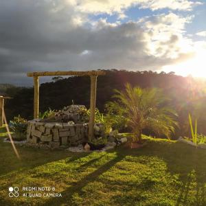 einen Garten mit einer Steinmauer und einer Pergola in der Unterkunft Chácara Cantinho do Ipê in Marechal Floriano