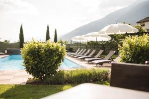 a pool with lounge chairs and umbrellas next to at Hotel Bauhof in Castelbello-ciardes