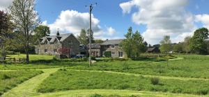 ein großes Haus auf einem grünen Feld mit einem Haus in der Unterkunft Maesyfelin Isaf B&B in Llanybyther