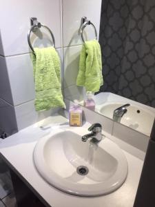 a bathroom sink with a green towel and a mirror at Apartamento Metro Santa Lucia, Santiago Centro in Santiago