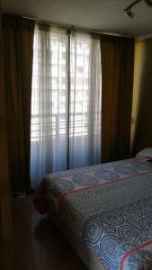 een slaapkamer met een bed en een raam met gordijnen bij Apartamento Metro Santa Lucia, Santiago Centro in Santiago