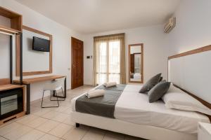 a bedroom with a bed and a desk and a television at Hotel Al Paradise in San Vito lo Capo