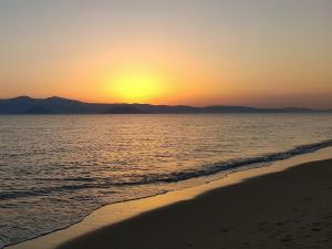 a beach with the sun setting in the distance at Dream on Plaka in Plaka