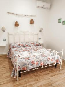 a white bed in a white bedroom with a wooden floor at Dafni e Naide in Cefalù