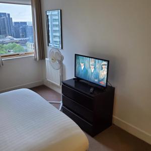 a bedroom with a bed and a flat screen tv at Captivating 2-Bed Apartment in Canary Wharf london in London