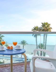 a table with two glasses and a view of the beach at KAKTUS Hotel Kaktus Albir in Albir