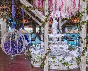 einen Brunnen und eine Statue in einem Zimmer mit Blumen in der Unterkunft Viktoriya Family Hotel Restaurant complex in Kiew