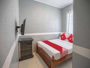 Schlafzimmer mit einem Bett mit roten Kissen und einem Fenster in der Unterkunft OYO 588 Sunrock Resort in Antipolo