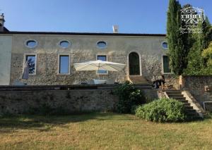 a stone house with an umbrella in front of it at Agriturismo Borgo Buzzaccarini Rocca di Castello in Monselice