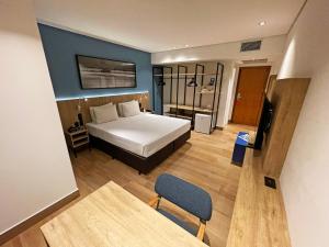 a bedroom with a bed and a table and a chair at Hotel Senac Ilha do Boi in Vitória