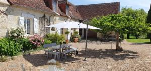 - une table de pique-nique et un parasol en face d'une maison dans l'établissement La Ferme Blanche, à Cussay