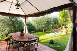 Tuscan countryside at the spa في Lari: فناء فيه طاولة وكراسي تحت مظلة