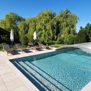 una piscina con sillas y sombrillas en un patio en La Ferme Blanche, en Cussay