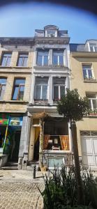 un edificio en una calle con un árbol delante en La maison des vacances, en Bruselas