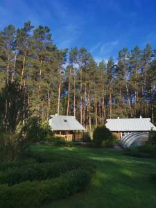two buildings in a field with trees in the background at Sigito sodyba in Jaskonys