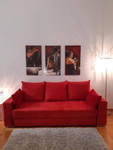 um sofá vermelho numa sala de estar com fotografias na parede em Apartment-Zimmer KRISTALL - großer Balkon und Parkplatz direkt im Zentrum em Bad Ischl