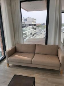 a couch in a living room with a large window at Ostend Port Side incl parking in Ostend