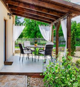 un patio con mesa y sillas bajo una pérgola de madera en Vintage apartman, en Mezőkövesd