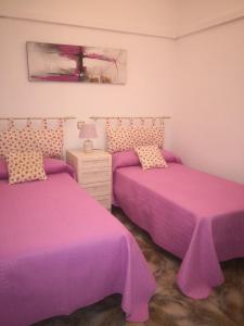 アルマグロにあるSanvarの紫のシーツが備わる客室内のベッド2台