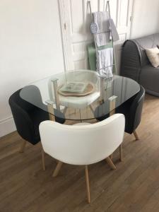 een glazen tafel en een witte stoel en een tafel en een bank bij Villa les Fleurs Appartement en front de mer in Mers-les-Bains