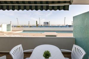 a patio with white chairs and a swimming pool at Miral 2 - Beach front apartment with pool in Quarteira