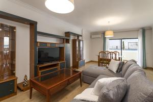 a living room with a couch and a tv at Miral 2 - Beach front apartment with pool in Quarteira