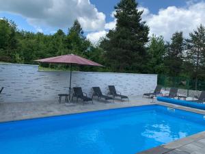 a blue swimming pool with chairs and an umbrella at Apartments Kristic in Grabovac