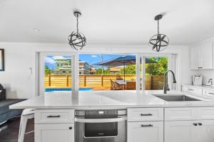 a white kitchen with a sink and a patio at Poolside Chic by the Sea in Ocean Bay Park