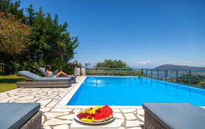 Eine Frau, die auf einem Stuhl neben einem Pool sitzt. in der Unterkunft Aloni Villas Sea View in Katouna