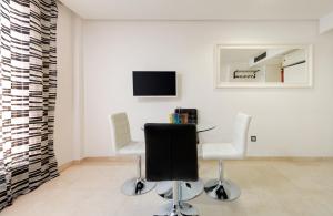 マドリードにあるRETIRO-IBIZA ALQUILER TEMPORAL-Hospitalesのテーブル、椅子2脚、テレビが備わる客室です。