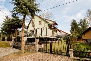 a house with a black fence and a tree at Dom z widokiem na jezioro Tajty - Wilkasy Zalesie in Giżycko