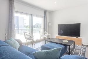 a living room with a blue couch and a tv at Apartamento T2 Tin Tin in Nazaré