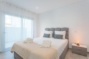 a white bedroom with a large bed and a window at Apartamento T2 Tin Tin in Nazaré +16 photos