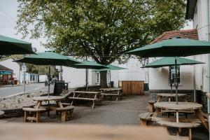 a group of picnic tables with green umbrellas at The Royal Oak in Heckington