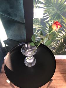un jarrón de cristal sobre una mesa negra con una rosa en Business Center, en Skierniewice