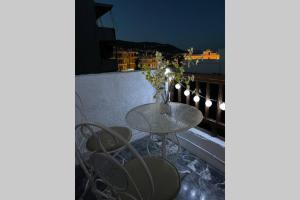 een tafel en stoelen op een balkon in de nacht bij RUSTIC DIAMOND new apartment near the beach in Porto Rafti
