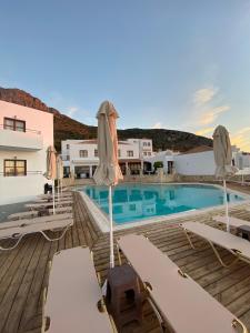 a pool with chairs and umbrellas on a wooden deck at Amazones Village Suites in Hersonissos