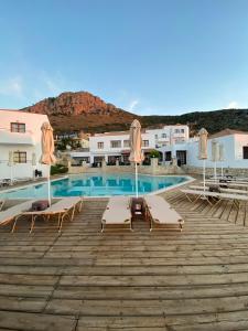 einen Pool mit Stühlen und Sonnenschirmen auf einer Holzterrasse in der Unterkunft Amazones Village Suites in Hersonissos