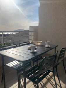 een zwarte tafel met 2 kopjes en stoelen op een balkon bij APPARTEMENT DUPLEX PORTICCIO Centre in Porticcio