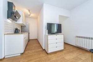 a kitchen with a refrigerator and a tv on a dresser at Hello Apartments Dworska LIGHT in Gdańsk +13 photos