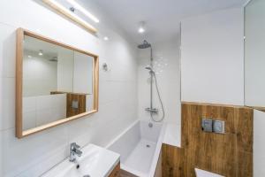 a bathroom with a tub and a sink and a mirror at Hello Apartments Dworska LIGHT in Gdańsk