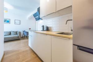 a kitchen with white cabinets and a counter top at Hello Apartments Dworska LIGHT in Gdańsk