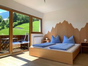 een slaapkamer met een bed en een groot raam bij Chalets und Apartments Hauserhof Nassfeld in Schlanitzen