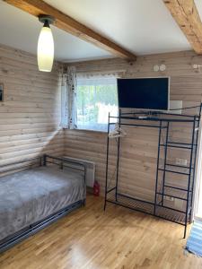 a bedroom with a bed and a flat screen tv at Pervalkos Dainava in Pervalka