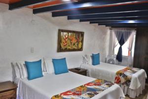 a bedroom with two beds with blue pillows at Hotel Mi Monaco in Pueblo Tapao
