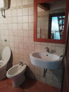 a bathroom with a sink and a toilet and a mirror at Piazzetta Del Forno - Monolocale con Soppalco in Assergi