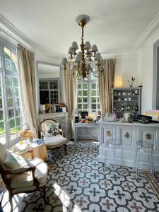 - un salon avec un lustre, une table et des chaises dans l'établissement Château de Noyelles – Baie de Somme, à Noyelles-sur-Mer